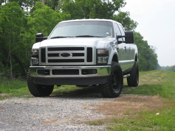 Silver 2008 Ford F-250 pickup truck parked on a gravel road with trees in the background