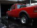 1997 Ford Ranger - A red pickup truck is parked on a wet driveway next to a garage.