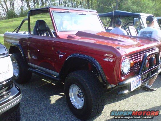 Red Ford Bronco with aftermarket hood scoop and roll cage. License plate says CRUISIN
