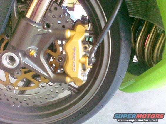 Close-up of a gold Tokico brake caliper and disc on a motorcycle wheel