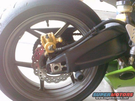 close up of motorcycle rear wheel, brake caliper, and chain guard
