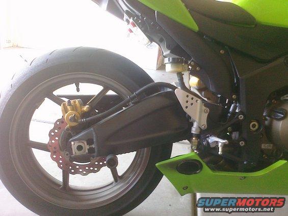 Motorcycle rear wheel with gold caliper and red disc brake, green fairing visible