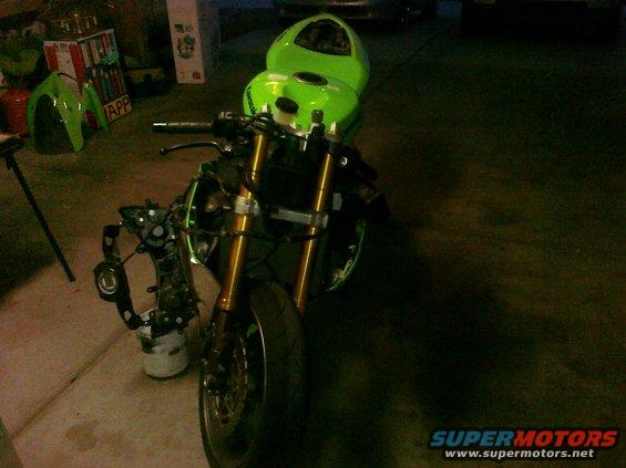 Green Kawasaki Ninja R motorcycle, front view, disassembled with front forks and engine components visible