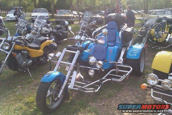 Blue trike motorcycle with chrome accents and a large seat, parked outdoors