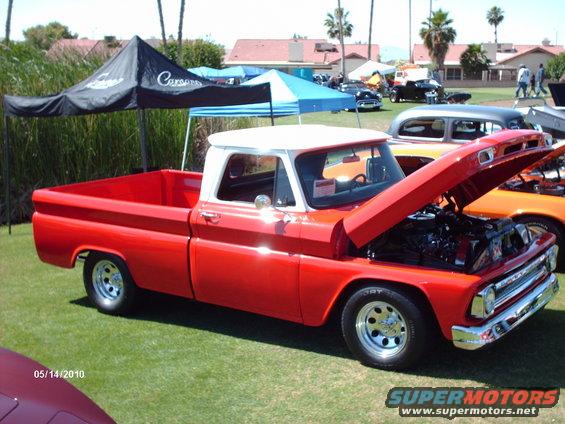 Red and white pickup truck, hood open, showing engine. Seen at car show