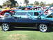 1992 Ford Bronco - A black convertible with custom blue flame graphics and chrome wheels is displayed at a car show, with other vehicles visible in the backgr…