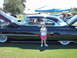 1992 Ford Bronco - A young girl poses next to a classic black coupe with its hood open at a car show.