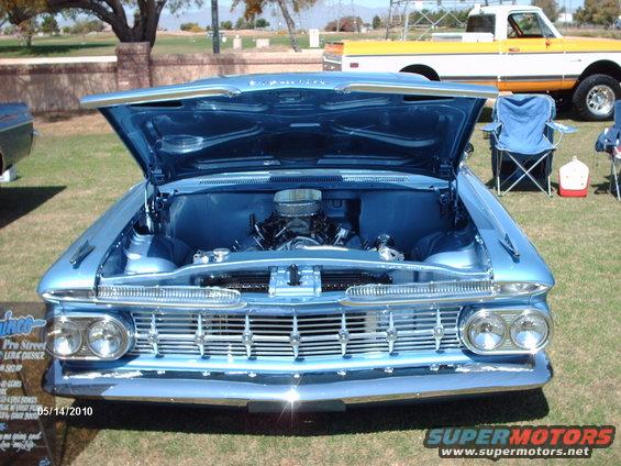 1959 Chevrolet Impala with hood open, showing engine. Yellow and white pickup truck in background