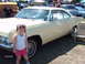 1992 Ford Bronco - A young girl poses in front of a pale yellow coupe at a car show, with other vehicles visible in the background.