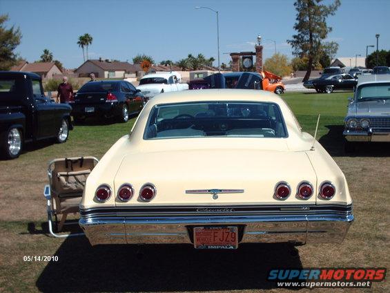 Rear of a cream-colored 1965 Impala with quad taillights and a vintage license plate