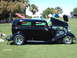 1992 Ford Bronco - A black sedan hot rod is displayed on a grassy field with its hood open.