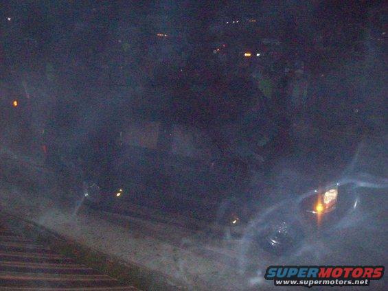 Dark SUV with headlights on, viewed from a low angle at night