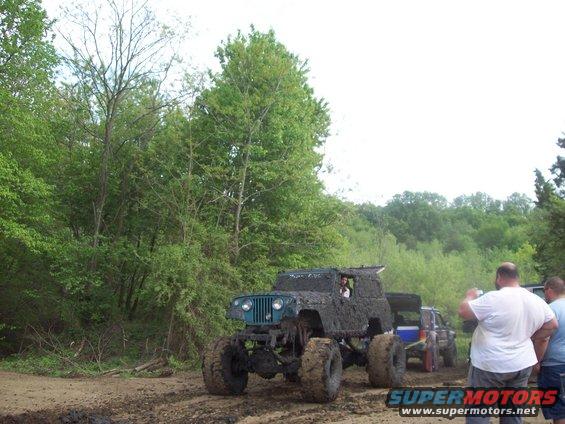 Mud-covered Jeep with large tires, front view