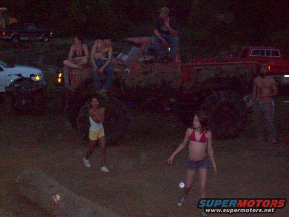 Muddy red truck with people gathered around at night