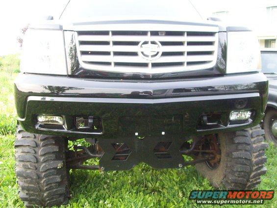 Front view of a lifted black Cadillac Escalade with large tires and a chrome grille