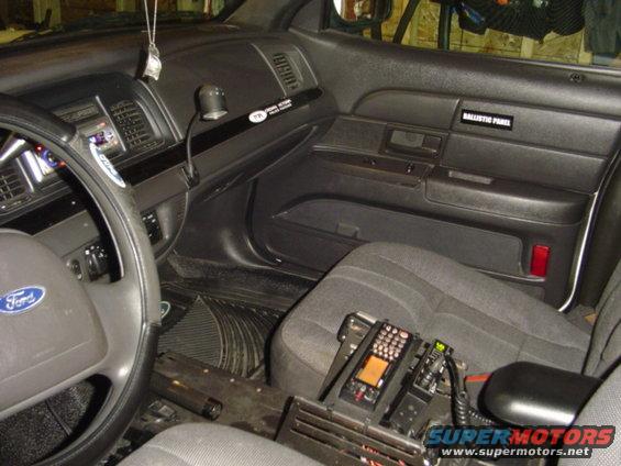 Interior of a 2003 Ford Crown Victoria police car showing the dashboard, steering wheel, and center console with radio equipment