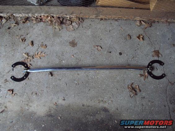 Car strut bar with horseshoe-shaped mounts on a concrete floor
