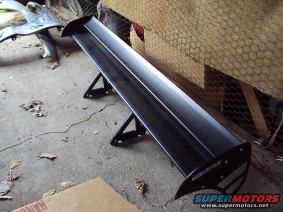 Black aftermarket car spoiler with "CKT" logo on a concrete floor