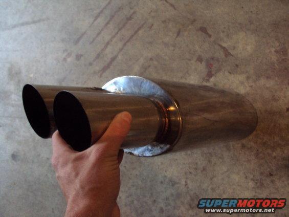 Hand holding a dual exhaust tip with a shiny metal finish
