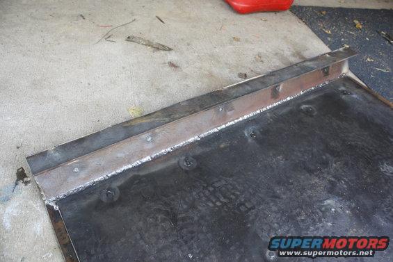 Welded metal plate with angle iron reinforcement along one edge, resting on concrete