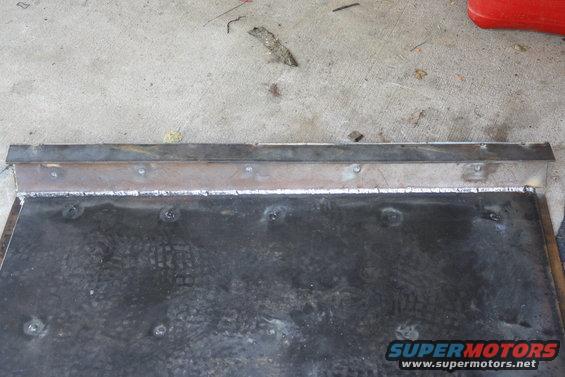 Welded metal plate with a metal strip attached to the top edge