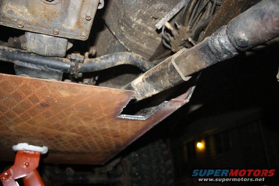 Underbody skid plate with cutouts, supported by a red jack