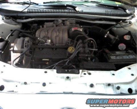 1997 Ford Taurus engine bay, white car, front view of engine components including alternator, intake manifold, and battery