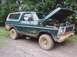 1979 Ford Bronco - Mud-covered 1970s Ford Bronco parked outdoors with its hood up, revealing the engine compartment.