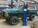 1979 Ford Bronco - Green 1978 Ford Bronco with white top and off-road tires is raised on a hydraulic lift in a garage.