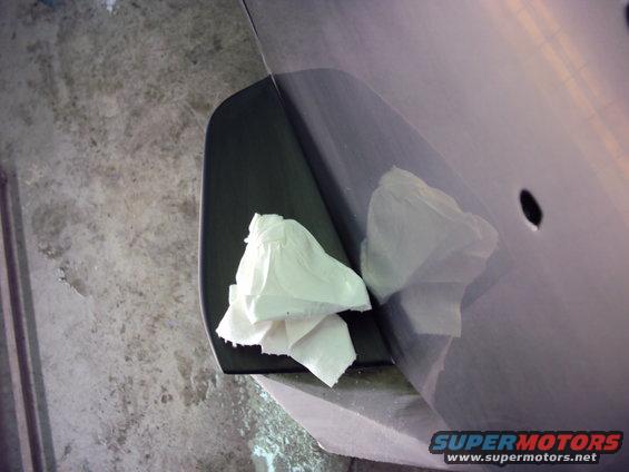 Close-up of a car's door panel with a black trim piece and white paper towels on it