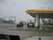 1986 Ford Bronco II - Two off-road vehicles are parked under a Shell gas station canopy during a snowfall.