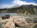 1986 Ford Bronco II - A classic 1986 Ford Bronco II sits near a tranquil lake, with a snow-capped mountain dominating the horizon.