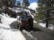 1986 Ford Bronco II - A brown SUV navigates a snowy, mountainous dirt road.