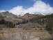 1986 Ford Bronco II - A scenic view of mountains with snow and red rock formations under a blue sky with clouds.
