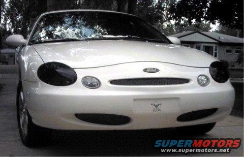 Front view of a white Ford Taurus with blacked-out headlights
