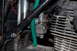2010 Kawasaki BAYOU 220 - This image shows a close-up view of a motorcycle's carburetor and engine block, with a green fuel line.
