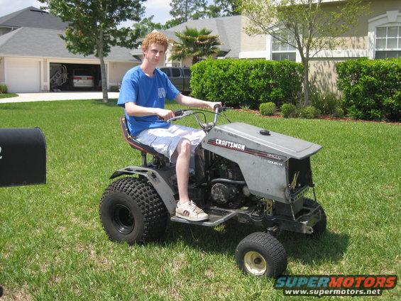 Gray Craftsman lawn tractor with a person riding it on a grassy lawn