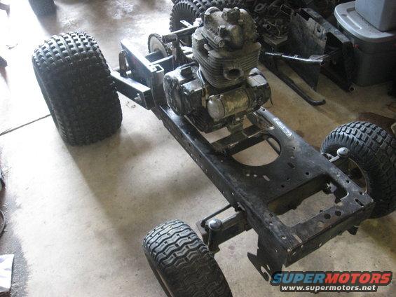 ATV frame with engine and four wheels, viewed from a 3/4 front angle