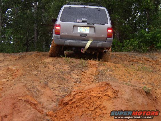 Jeep Grand Cherokee on a dirt trail, rear view, with a tow strap attached