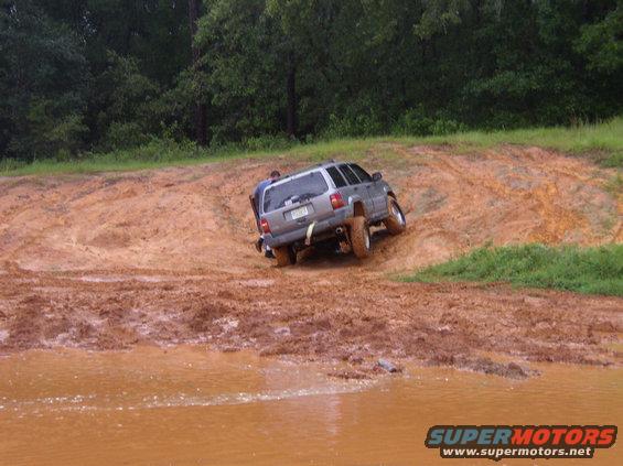 Silver SUV stuck in mud with a person pushing
