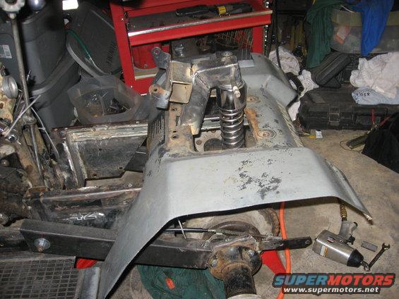 ATV frame with suspension spring visible, undergoing repair in a garage