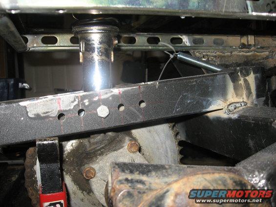 Close-up of vehicle frame with suspension shock, spring, and chain drive