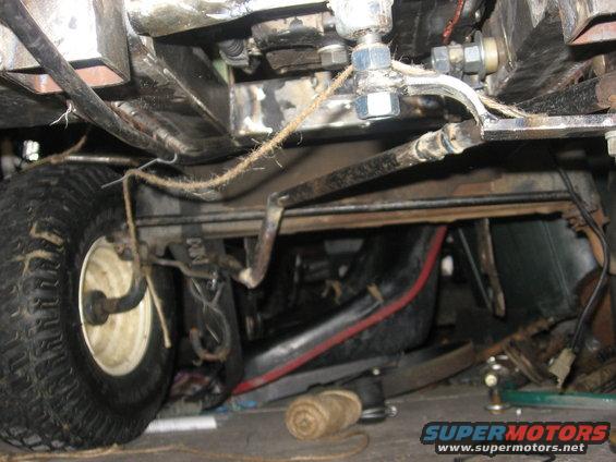 Undercarriage of a vehicle with a tire, hoses, and metal frame visible