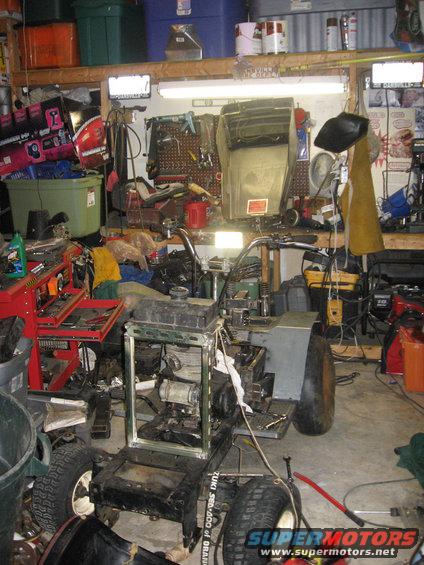 Front view of a disassembled lawn tractor with visible engine and frame