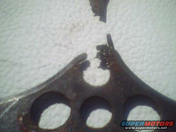 close-up of a broken, rusty metal piece with several circular cutouts