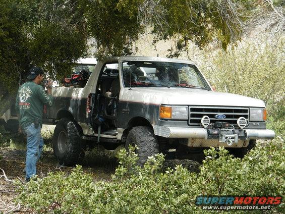 Ford Bronco with a winch on the front bumper, parked off-road with a person taking a photo