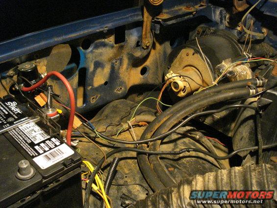 Close-up of engine bay wiring and a car battery with red cables