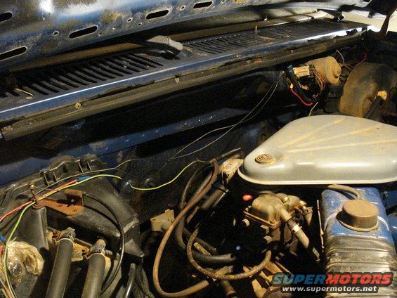 Close-up of engine bay wiring, showing hoses, carburetor, and air cleaner housing