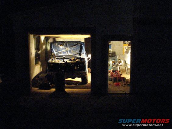 Truck in garage with hood up, another vehicle visible in background