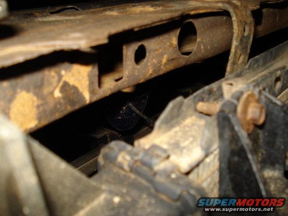 Wiring harness tucked behind rusty frame components